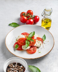 Caprese salad with sliced ​​tomatoes, mozzarella and basil  on a light background