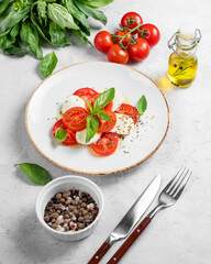 Caprese salad with sliced ​​tomatoes, mozzarella and basil  on a light background