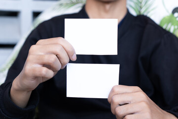A man wearing a black shirt holding white blank business card mockup