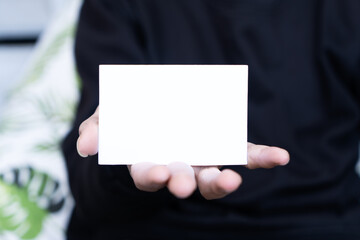 Obraz premium A man wearing a black shirt holding white blank business card mockup