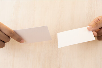 Obraz premium Hand holding white blank business card mockup on wooden background