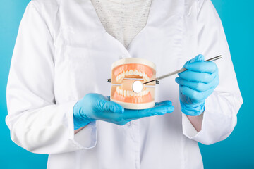 Dentist hand with dentist tools and healthy white tooth model on background. Dental care, dental...
