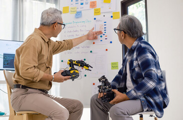 asian Engineers discussing robotics prototype with teamwork and innovation in artificial technology...