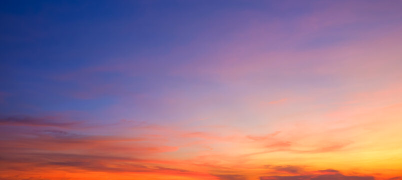 Evening sky background after sundown with dramatic dusk clouds and colorful orange yellow natural light on blue twilight sky, Beautiful summer sunrise panoramic sky backdrop