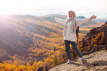 Freedom Traveler Woman with Backpack standing with Raised arms and enjoying beautiful nature