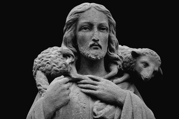 Ancient statue of Jesus Christ is the Good Shepherd with the lost sheep on his shoulders.  Close up.