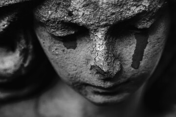 Crying angel as symbol of pain, fear and end of human life. Fragment of an ancient statue. Black...