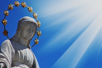 Close up Virgin Mary against blue sky. Fragment of ancient statue. Religion, faith, Christianity...