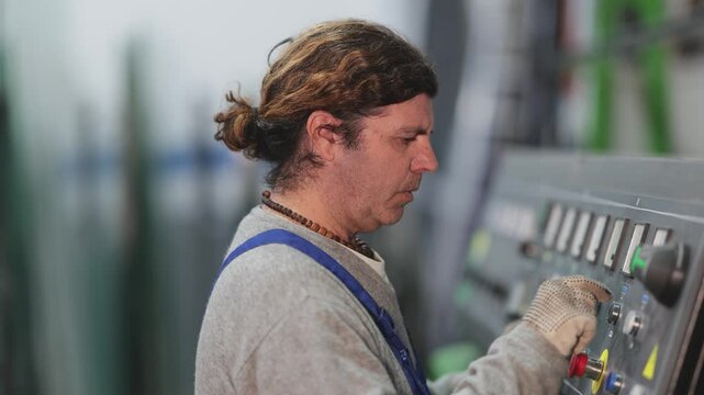 During production cycle, man worker changes initial data to control board, controls mechanisms by turn on relays. Employee works at center control panel