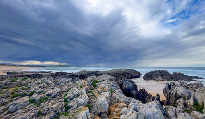 Dramatic seascape with dark storm clouds gathering over a rocky coastline and waves crashing gently...