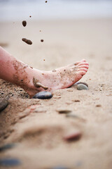 Close-up of sandy child foot on beach with falling sand