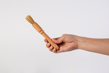 Hand using a wood little paintbrush isolated on a white background