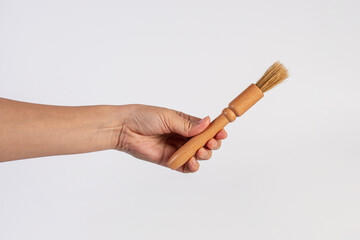 Hand using a wood little paintbrush isolated on a white background