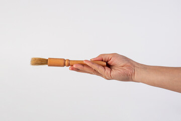 Hand using a wood little paintbrush isolated on a white background