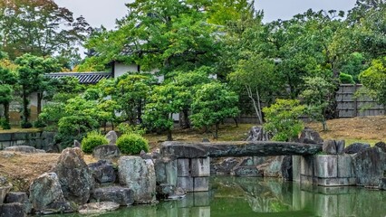 Japanese garden with stone bridge and pond.