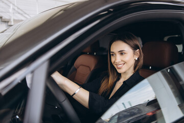 Businesswoman smiling while driving a new car at the dealership