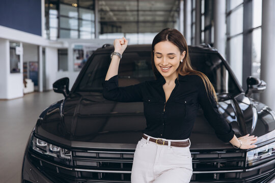 Saleswoman celebrating selling new car in car dealership