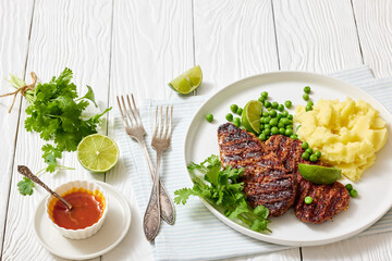 grilled beef cutlets with potato mash, green peas