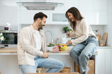 A couple enjoys playful cooking moments in a bright and inviting kitchen filled with fresh ingredients and love.