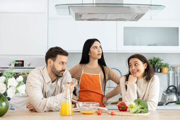 In a vibrant kitchen, a woman leads a discussion with two friends, showcasing the importance of collaboration while cooking.