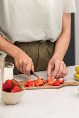 Woman cutting strawberries. Preparing fresh berries for a healthy breakfast 