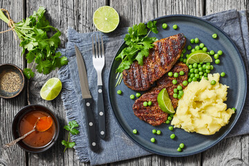 grilled beef cutlets with potato mash, green peas