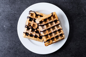 Belgian Waffles with chocolate on black slate background. Top view