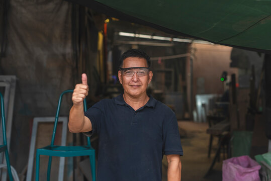 Experienced artisan gives a thumbs up in a small-scale woodworking shop, showing satisfaction and confidence in handmade furniture production. - Powered by Adobe
