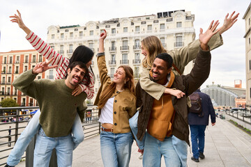 multiethnic friends giving piggyback rides in city center