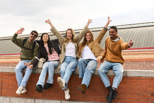 Happy students raising arms and smiling at atocha station