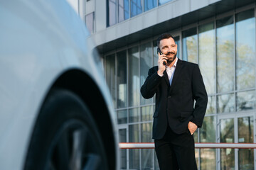 Young traveler businessman man in suit standing outside in international airport terminal near taxi car talking on mobile phone. Business trip concept.