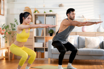 Fitness coach guidance with asian woman during squat training at home in living room, workout and exercise for healthy lifestyle, instructor and body strength coaching, practice stretching of muscle.