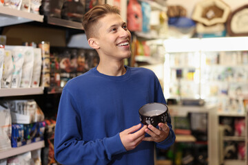 Happy man with feeding bowl in pet shop