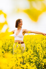 Fototapeta premium Woman enjoying a sunny day in a field of yellow flowers