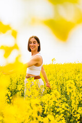 Fototapeta premium Woman enjoying a sunny day in a field of yellow flowers