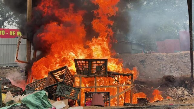 Intense flames engulfing wooden furniture and plastic boxes in polluting outdoor fire, Hanoi, Vietnam.