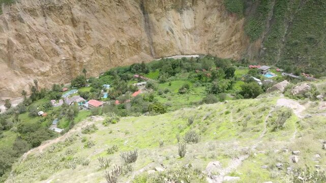 Close-up drone shot from the midway point of the descent, revealing the winding path toward Sangalle, surrounded by the dramatic cliffs of Colca Canyon and the lush oasis in the distance.