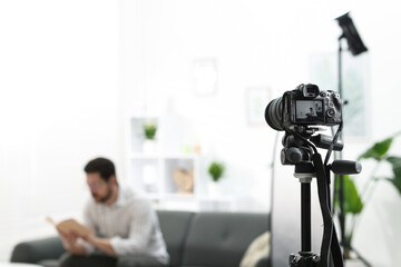 Man sitting on sofa in studio, focus on video camera recording him