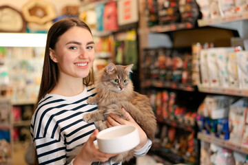 Woman with her cute cat and feeding bowl in pet shop. Space for text