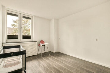 A serene nursery showcasing minimal decor with natural light streaming through large windows. Featuring a crib and wooden flooring, it exemplifies simplicity and elegance.