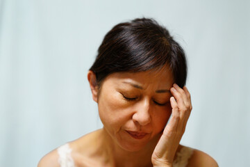 額に手を当てる中年女性