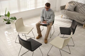 Professional psychologist in room with chairs prepared for group counseling, above view