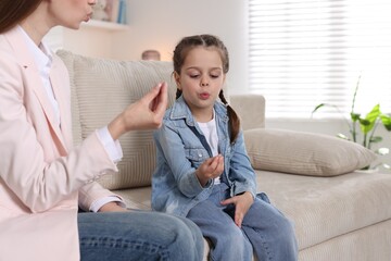 Speech therapist working with little girl indoors, closeup