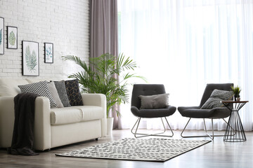 Fototapeta premium Comfortable sofa and chairs near window with elegant curtains in room