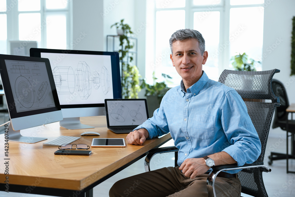 Poster portrait of smiling engineer at table with devices in office