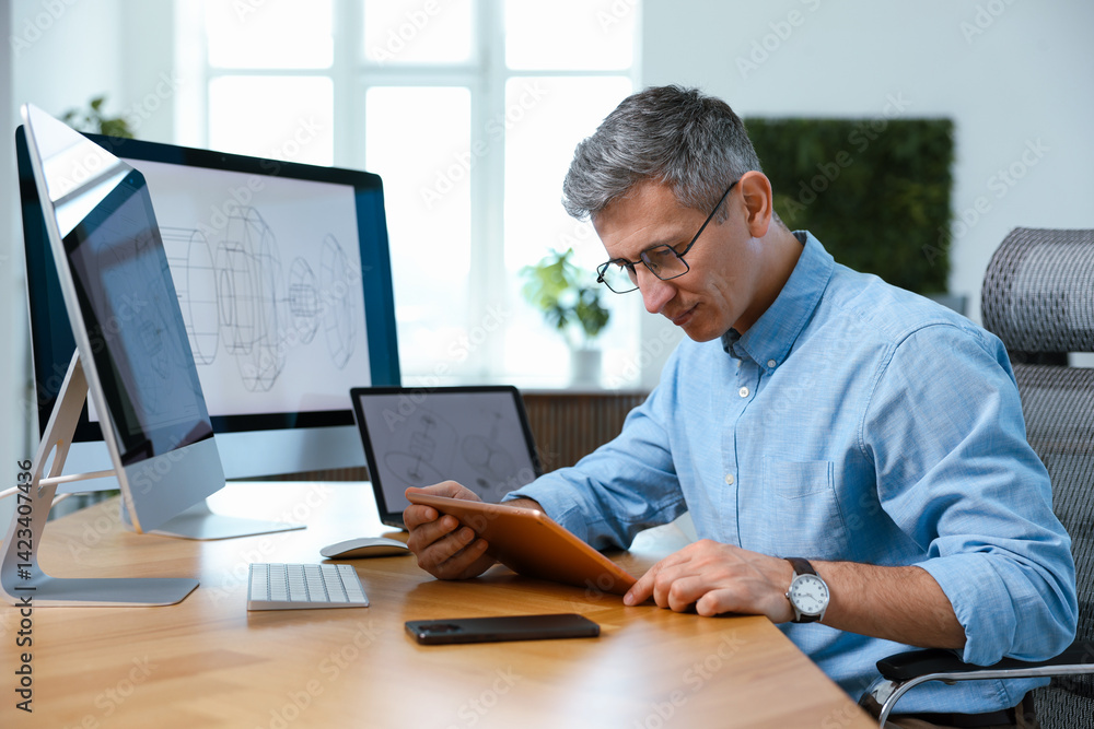 Poster engineer working with devices at table in office