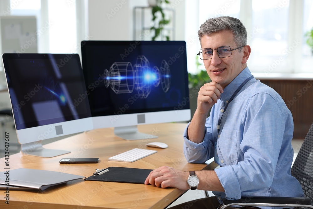 Poster portrait of smiling engineer at table with monitors in office