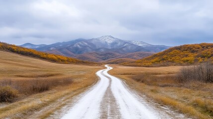 Winding road through autumnal landscape, snow-capped mountains