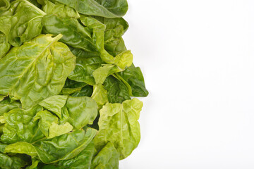 Fresh green spinach leaves are arranged along the left edge of a white background, leaving ample...