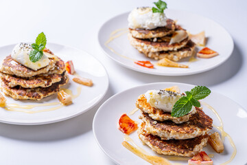 Healthy, dietary breakfast. Cottage cheese pancakes with cream cheese, orange, honey and mint on a white plate and background.